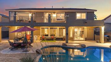 A two-story house with a swimming pool, outdoor seating, and a patio area.