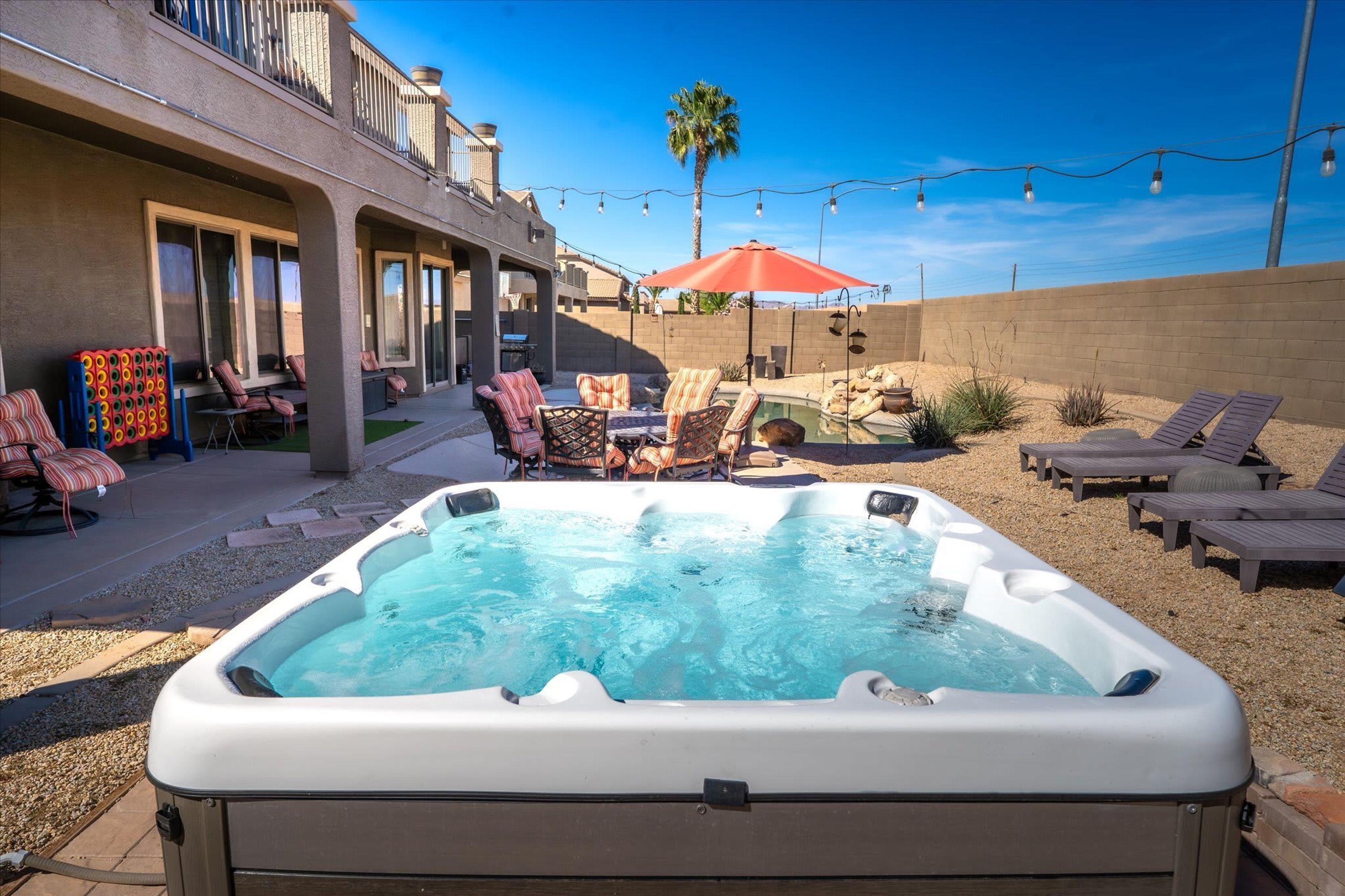 Jacuzzi con sillones de descanso y zona de barbacoa en un patio trasero.