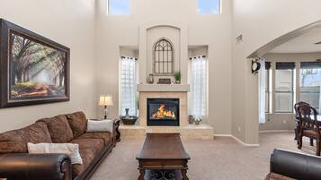 A living room with a fireplace, a large painting, and a view of the outdoors.