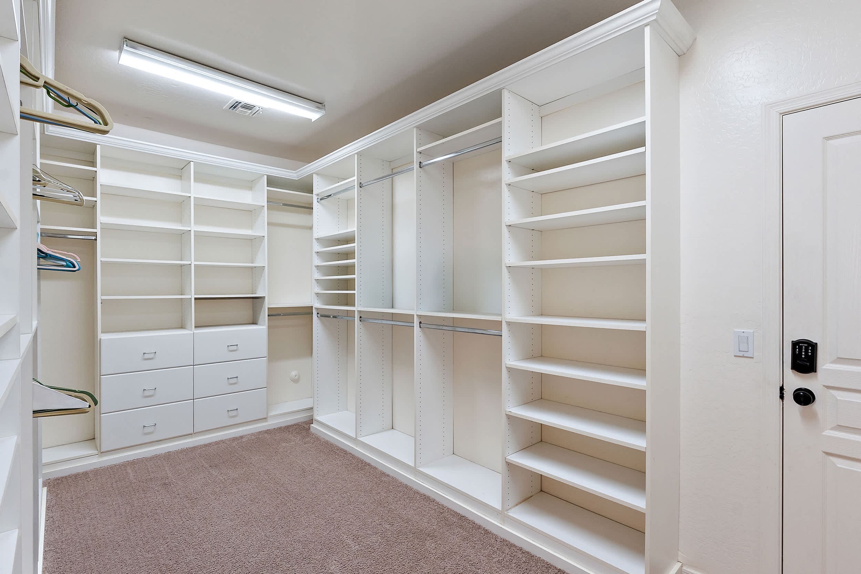 A walk-in closet with multiple shelves, drawers, and hanging space.