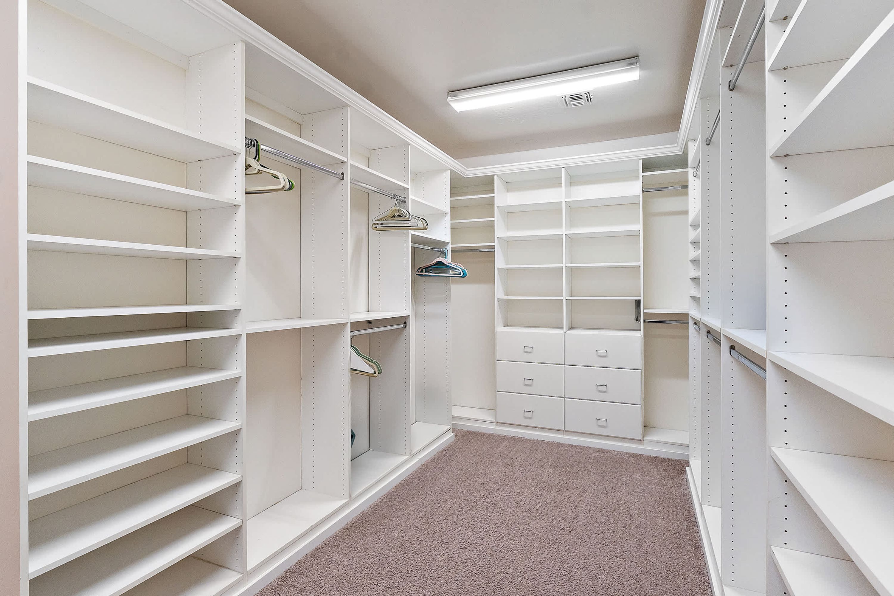 A walk-in closet with open shelving, hanging space, and drawers.