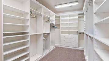 A walk-in closet with open shelving, hanging space, and drawers.