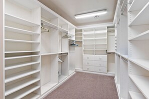 Ein begehbarer Kleiderschrank mit offenen Regalen, Kleiderstange und Schubladen.