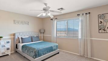 A bedroom with a bed, a nightstand, a ceiling fan, a window with blinds, and a decorative wall piece.