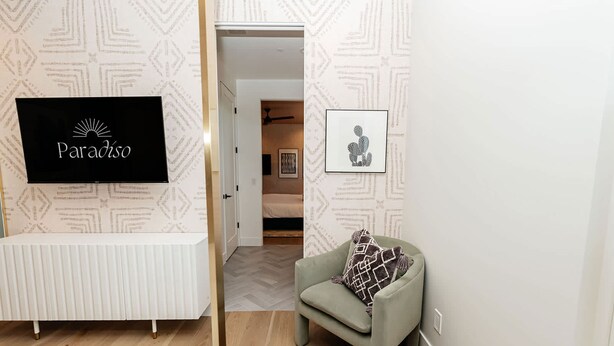 Ein Hotelzimmer mit einem Bett, einem Sessel, einem Fernseher und einem gerahmten Bild an der Wand.