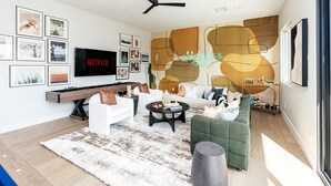 Ein modernes Wohnzimmer mit einem Flachbildfernseher, einem Deckenventilator und verschiedenen gerahmten Bildern an der Wand.