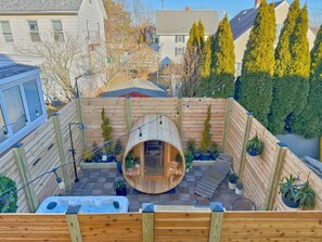 Una terraza de madera con un jacuzzi, una estructura de madera que recuerda a un barco y plantas en macetas.