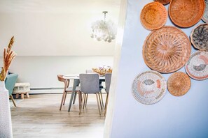 Un comedor moderno con una mesa, sillas y una pared decorativa con elementos tejidos.