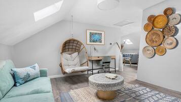Ein modernes Schlafzimmer im Loft-Stil mit Hängekorbschaukel, rundem Couchtisch und Schreibtisch.