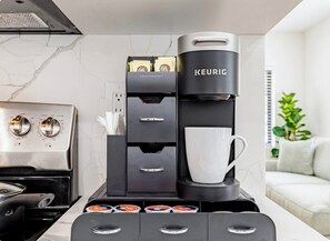 Eine moderne Küche mit einer Keurig-Kaffeemaschine, einem Kaffee-Pod-Halter und einer weißen Tasse.