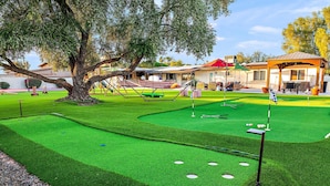 A golf course with a putting green, sand bunkers, and a large tree. - The Desert Reserve Pool Sport Court 7BR (Scottsdale)