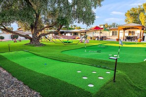 A golf course with a putting green, sand bunkers, and a large tree. - The Desert Reserve Pool Sport Court 7BR (Scottsdale)
