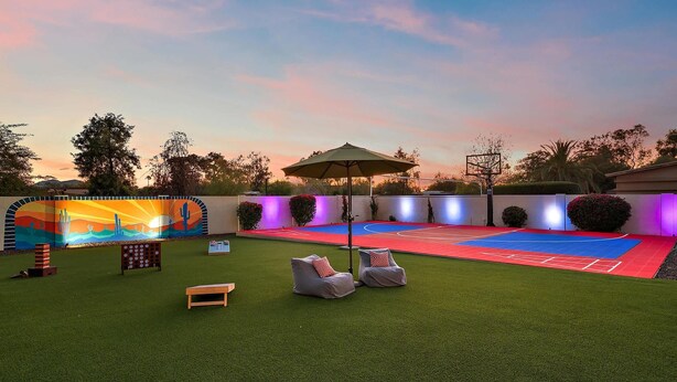 An outdoor space with artificial turf, seating, and a mural. - The Desert Reserve Pool Sport Court 7BR (Scottsdale)