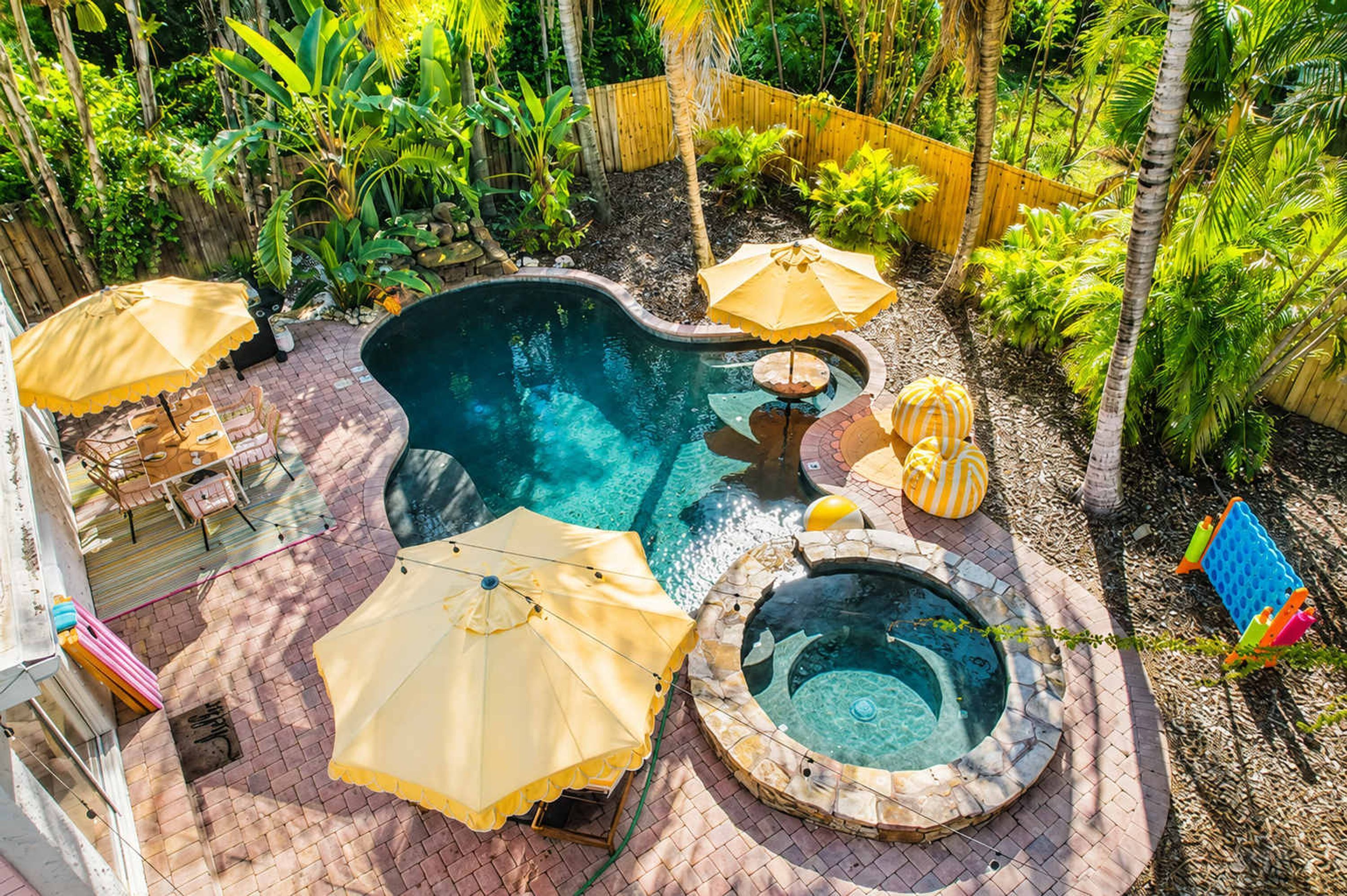 A pool area with a hot tub, umbrellas, and lounge chairs.