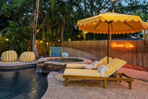 A poolside area with lounge chairs and a canopy, surrounded by a wooden fence and palm trees. - Bradenton Bliss Heated Pool Hot Tub Games (Bradenton)
