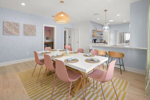 A modern dining area with a white table, pink chairs, and a yellow striped rug. - Bradenton Bliss Heated Pool Hot Tub Games (Bradenton)