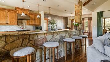 A kitchen with wooden cabinets, a stone island with bar stools, and a stone fireplace.