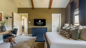 A bedroom with a bed, a desk, a chair, a television, and a dresser. - Stillstone Ranch A Wellness Retreat Sleeps 32 (Driftwood)