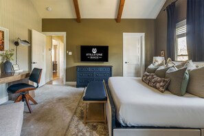 A bedroom with a bed, a desk, a chair, a television, and a dresser. - Stillstone Ranch A Wellness Retreat Sleeps 32 (Driftwood)