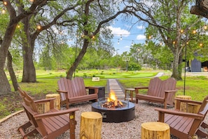 An outdoor seating area with Adirondack chairs, a fire pit, and a view of a golf course. - Stillstone Ranch A Wellness Retreat Sleeps 32 (Driftwood)