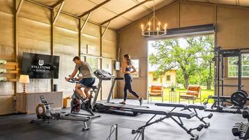 A gym with treadmills, weights, and a TV screen displaying 'STILLSTONE RANCH 2023'.