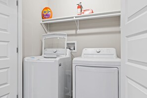 A laundry area with two white washing machines and a shelf above containing Tide detergent and a fire extinguisher. - MTN Views Hot Tub Games Dog Friendly (Ellijay)