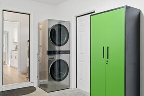 A laundry room with a stainless steel washer and dryer, a green wardrobe, and a white door. - Epic Backyard - Pool - Hot Tub - Outdoor Theatre (Bradenton)