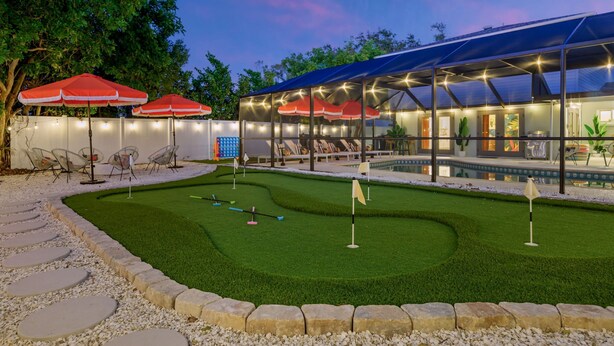 Un espacio exterior cuidado con piscina, césped artificial y zonas de estar.
