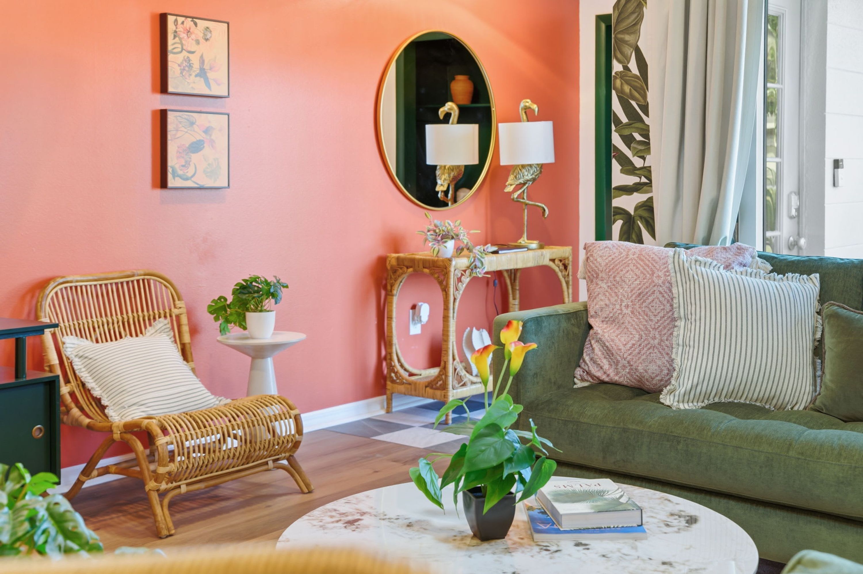 A cozy living room with a wicker chair, a green sofa, and a round coffee table with a plant and books.