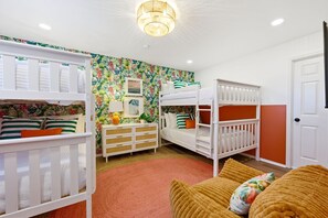 A children's room with bunk beds, a dresser, and a wall with a tropical print. - Epic Backyard - Pool - Hot Tub - Outdoor Theatre (Bradenton)