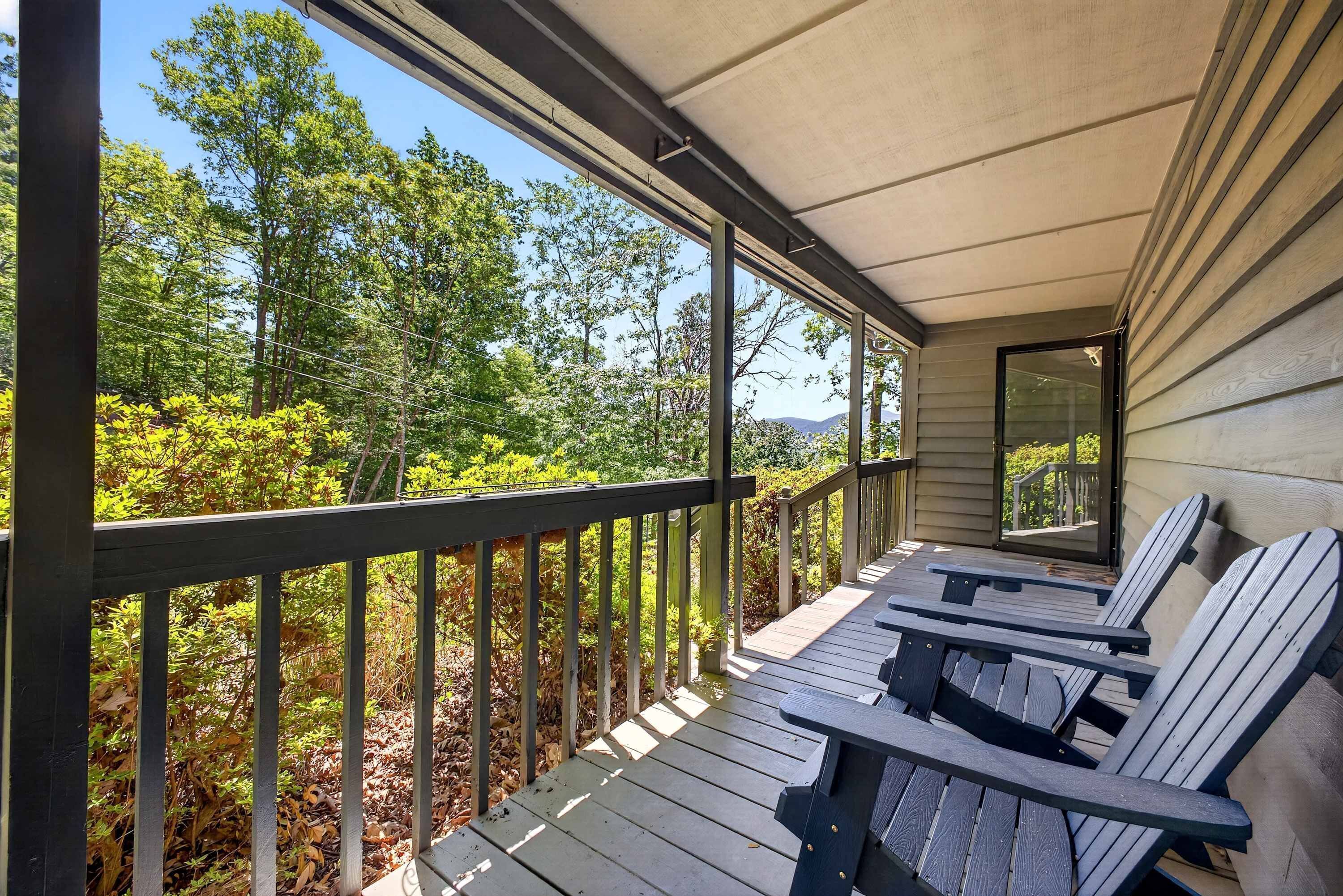A covered porch with wooden railings, a bench, and a table.