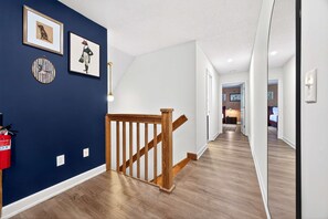 Ein Flur mit einer Holztreppe, weißen Wänden und einer blauen Akzentwand.