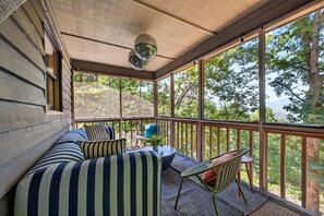 A covered porch with a cushioned seating area, a small table, and a chair. - Mtn Cabin w Sauna Hot Tub Outdoor Fun (Swannanoa)