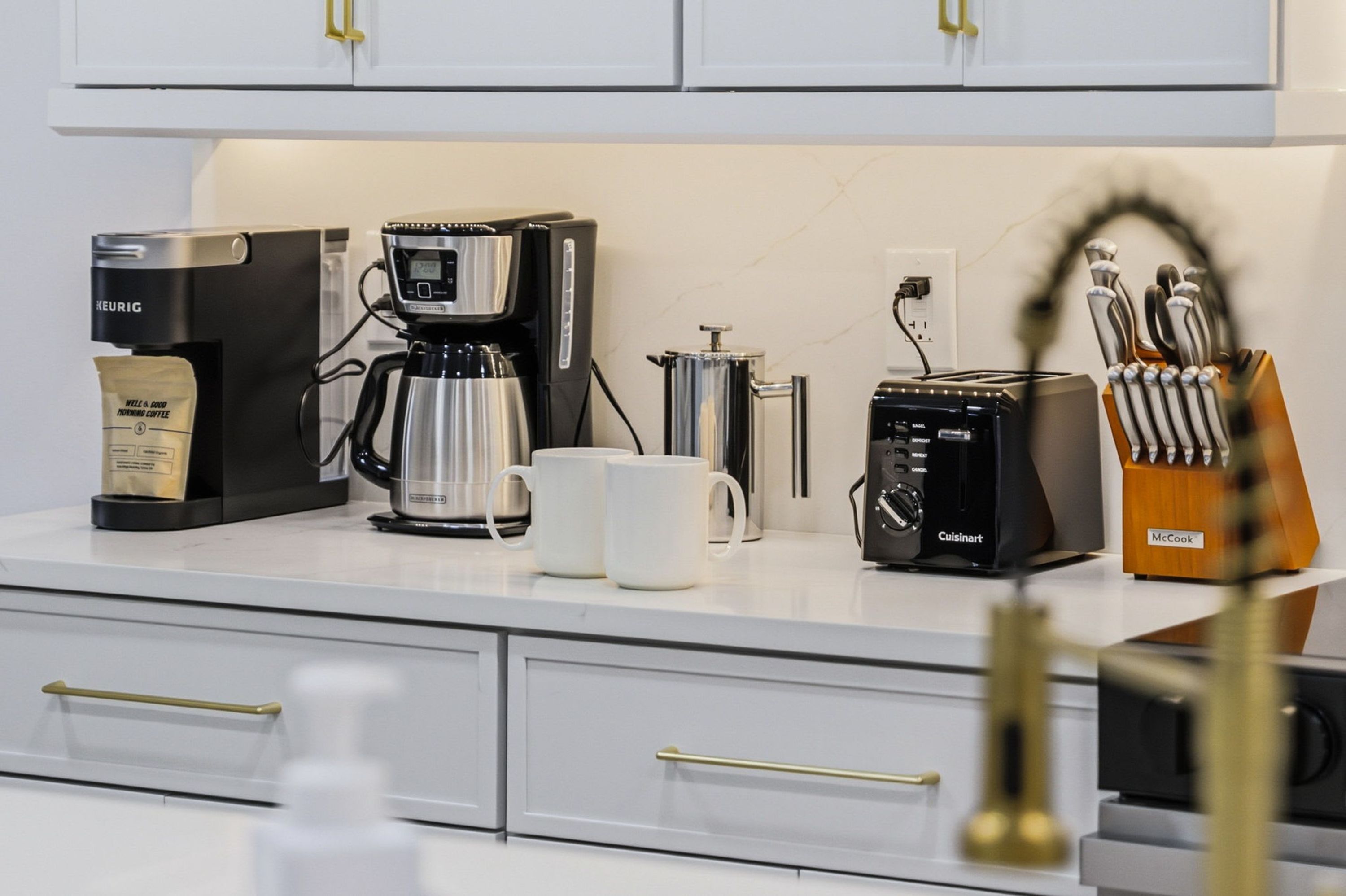 Un bancone da cucina con una macchina per il caffè Keurig, un tostapane Cuisinart, una caffettiera e un sacchetto di caffè.