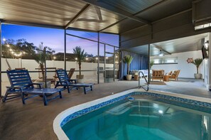 A swimming pool with lounge chairs and a covered patio area. - Breezy Livin - Speakeasy - Pool - Spa - Game Room (Bradenton)