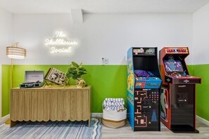 Ein Zimmer mit einer Neonreklame, Spielautomaten, einem Plattenspieler im Vintage-Stil und einer grünen Wand.
