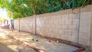 Un terrain de pétanque avec un mur en briques et une bordure en bois.
