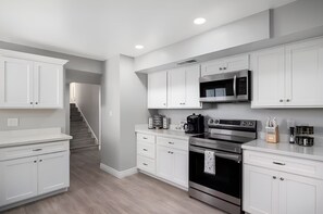 A modern kitchen with white cabinetry, a built-in microwave, a coffee maker, and an oven. - The Cactus Rose Heated Pool Putterball Bocce (Glendale)