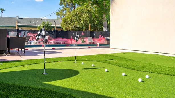 Un espace recouvert d’une pelouse artificielle bien entretenue, agrémenté d’un green d’entraînement et de balles de golf, ce qui laisse supposer qu’il s’agit d’un lieu de loisirs.