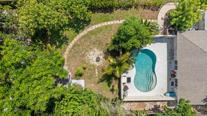 An aerial view of a property with a swimming pool, surrounded by lush greenery and a paved deck area. - Sleeps 6 Private Pool Fire Pit Game House (Sarasota)
