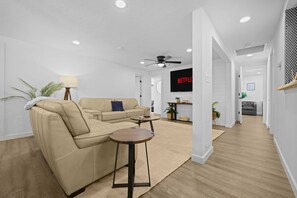 Ein modernes Wohnzimmer mit einer Couch, einem Couchtisch und einem an der Wand befestigten Fernseher.