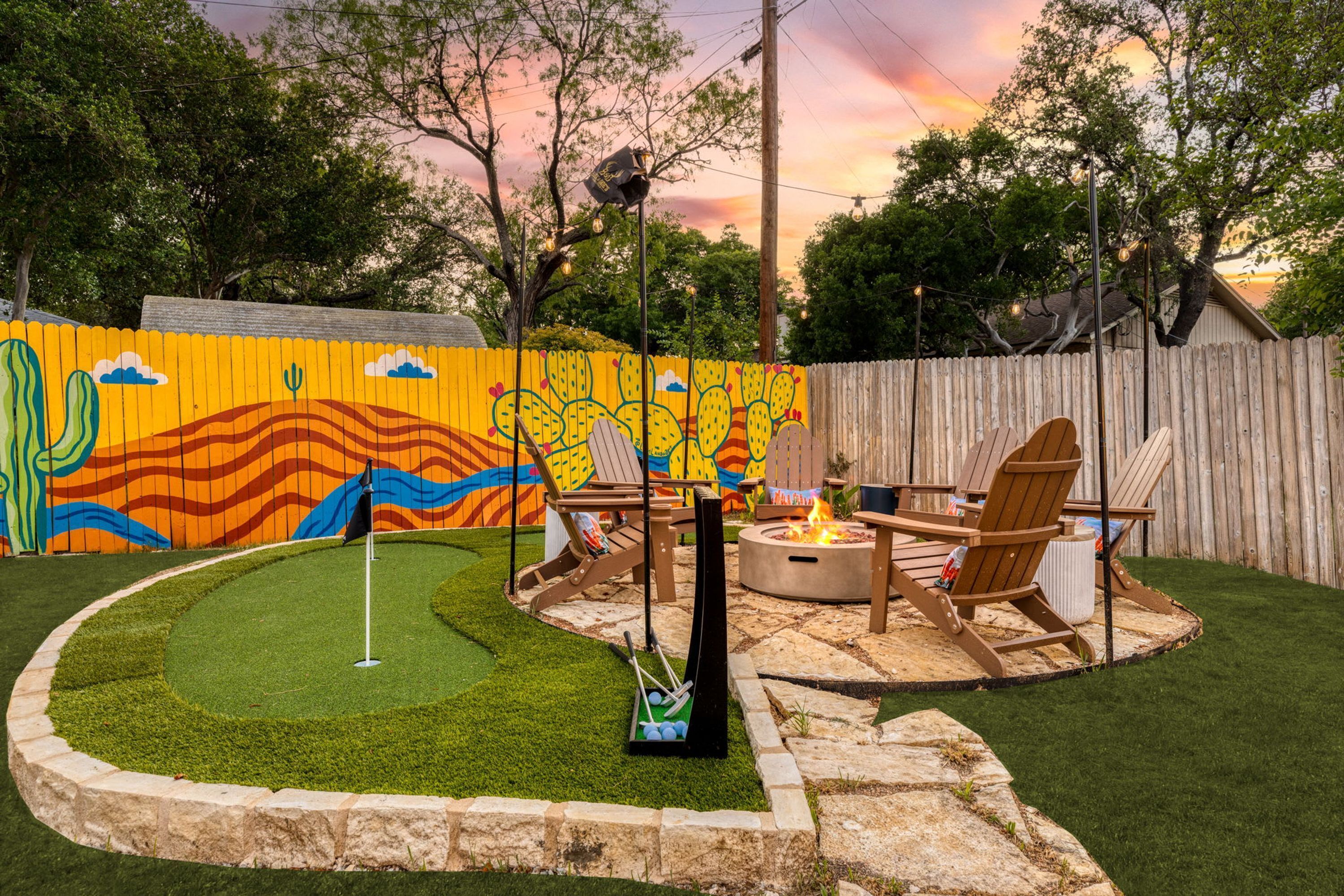 Un patio trasero con campo de práctica de golf, una fogata y mobiliario para exteriores.