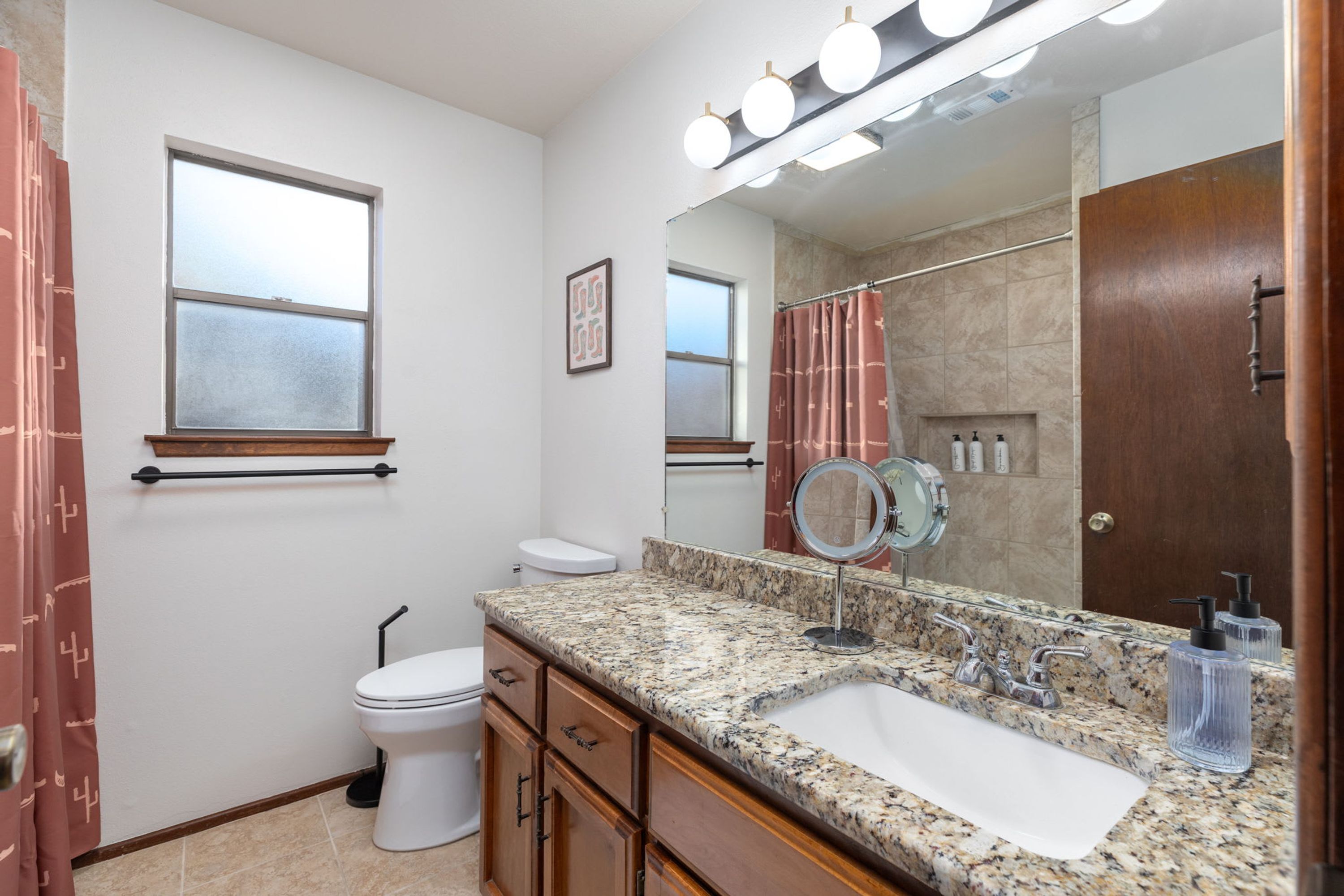Une salle de bain comprenant des toilettes, un lavabo, un meuble-lavabo et un miroir.