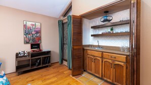 Una cocina compacta con armarios de madera, una estantería empotrada con vasos y un cuadro en la pared.