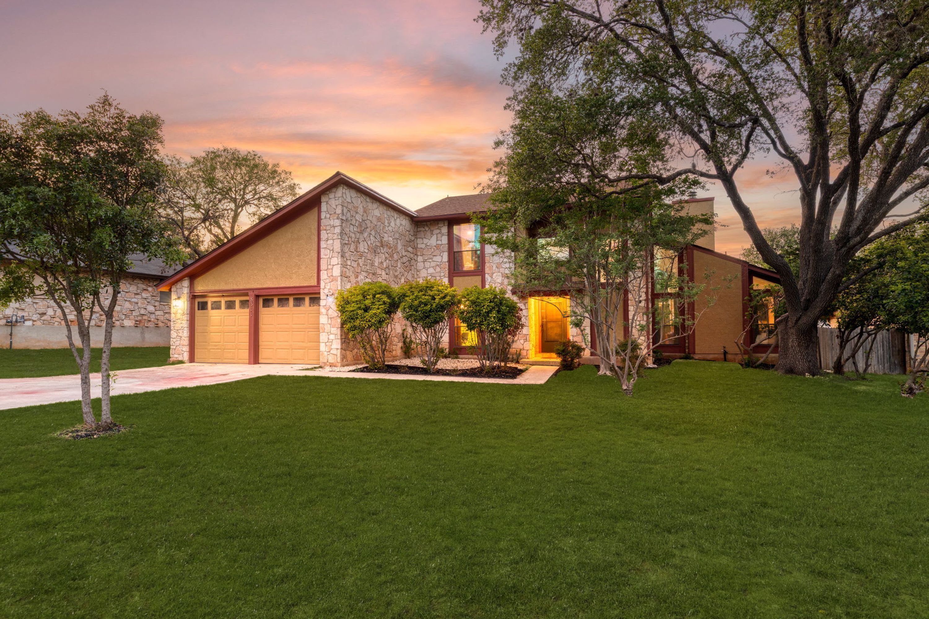 A modern two-story house with a stone facade, a garage, and a well-maintained lawn.