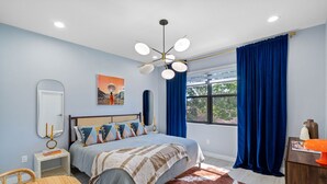 A bedroom with a bed, a nightstand, a mirror, a window with curtains, and a cowhide rug. - Close to DT Tampa Newly Designed Town Home (Tampa)
