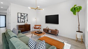 A modern living room with a green sofa, a coffee table, a TV, and a plant. - Close to DT Tampa Newly Designed Town Home (Tampa)