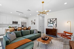 Un salon moderne comprenant un canapé, une table basse et un coin repas avec des chaises.