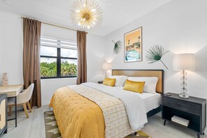 A hotel room with a bed, bedside tables, a desk, and a view of greenery outside. - Close to DT Tampa Newly Designed Town Home (Tampa)