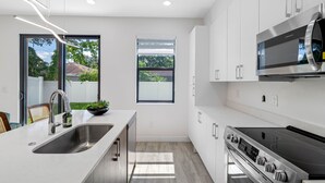 A modern kitchen with a stainless steel sink, a built-in oven, and a microwave. - Close to DT Tampa Newly Designed Town Home (Tampa)